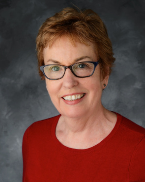 Color headshot of Mary Adamek wearing eyeglasses and red shirt