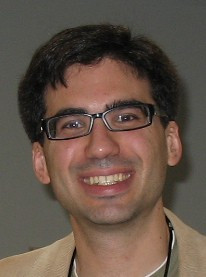 Color headshot of Juan Pablo Hourcade smiling, wearing eyeglasses and brown jacket