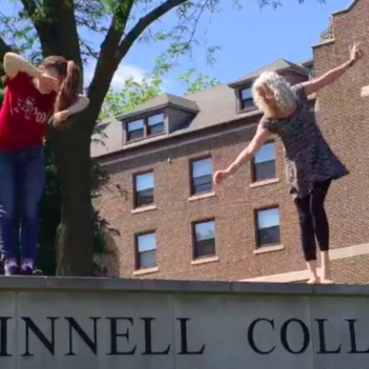 Photo of Celeste Miller and Charlotte Richardson-Deppe dancing on Grinnell College sign